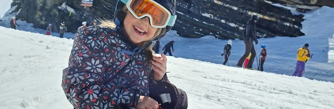 Petite fille équipée d'un casque, de lunettes et de bâtons de ski loués chez Loca-Ski